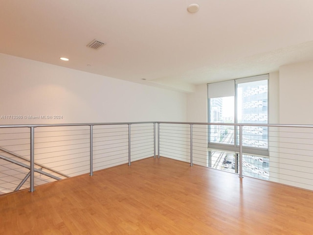 empty room with floor to ceiling windows and light hardwood / wood-style flooring