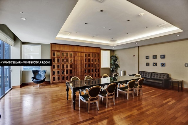 dining space with a raised ceiling and wood-type flooring