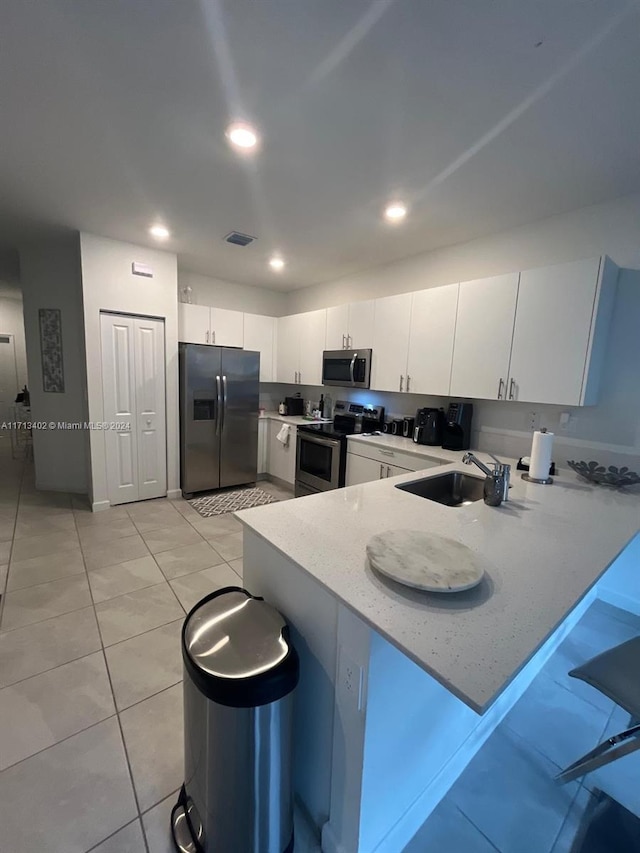 kitchen with white cabinets, appliances with stainless steel finishes, kitchen peninsula, and sink