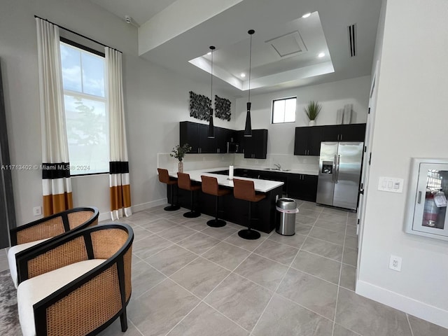 kitchen featuring kitchen peninsula, a kitchen breakfast bar, stainless steel appliances, a tray ceiling, and plenty of natural light