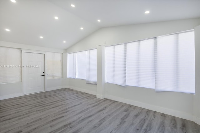 spare room with lofted ceiling and light wood-type flooring