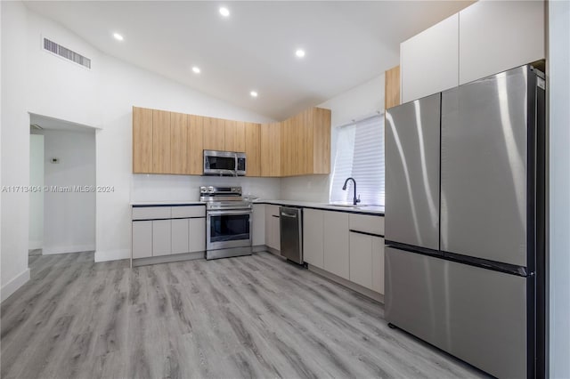 kitchen featuring sink, vaulted ceiling, light brown cabinetry, white cabinetry, and stainless steel appliances