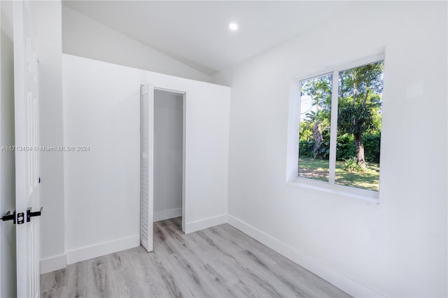 unfurnished bedroom featuring light wood-type flooring, vaulted ceiling, and a closet