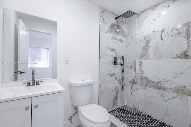 bathroom with a tile shower, vanity, and toilet