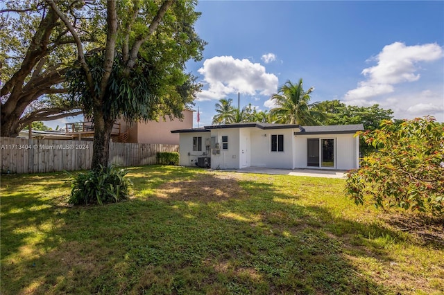 rear view of house with a patio area, a yard, and central AC