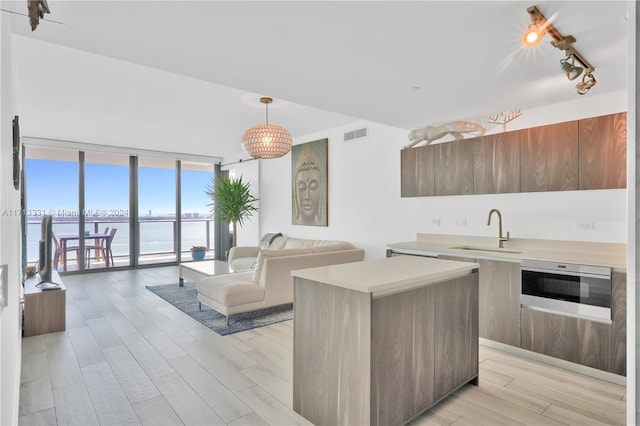 kitchen featuring sink, a water view, a wall of windows, a center island, and oven