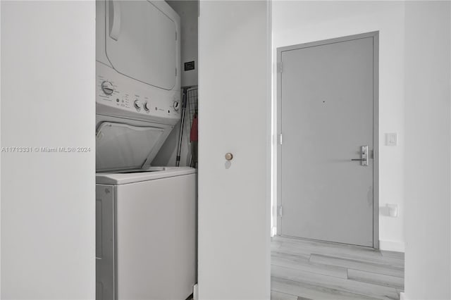 laundry area with stacked washing maching and dryer and light hardwood / wood-style flooring