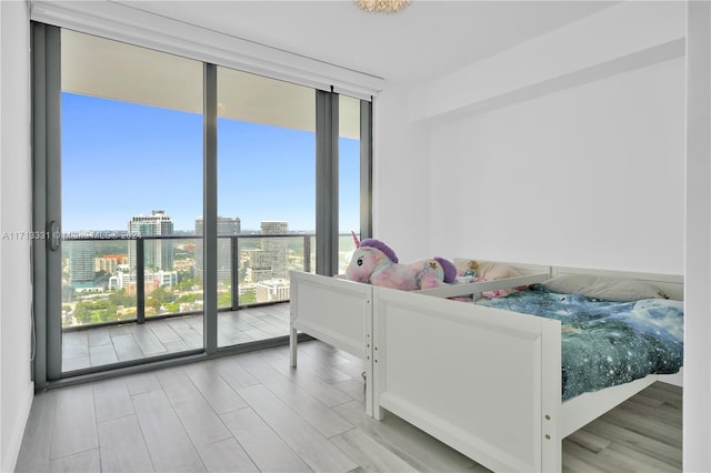 bedroom with light hardwood / wood-style floors and a wall of windows