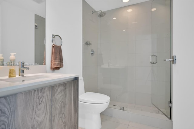 bathroom with tile patterned floors, vanity, a shower with shower door, and toilet