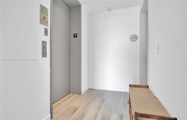 corridor featuring light wood-type flooring and elevator