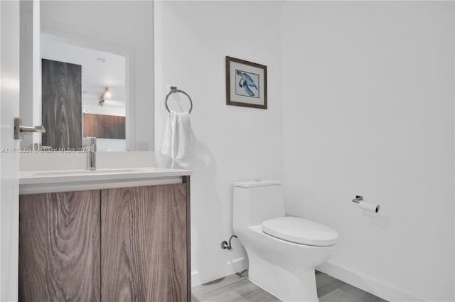 bathroom featuring vanity, hardwood / wood-style flooring, and toilet