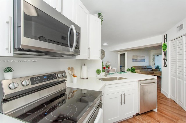 kitchen with sink, white cabinets, light wood-type flooring, and appliances with stainless steel finishes