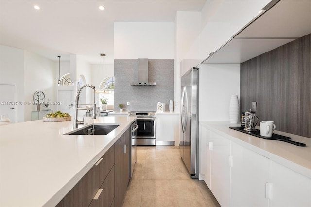 kitchen with appliances with stainless steel finishes, wall chimney exhaust hood, dark brown cabinets, sink, and pendant lighting