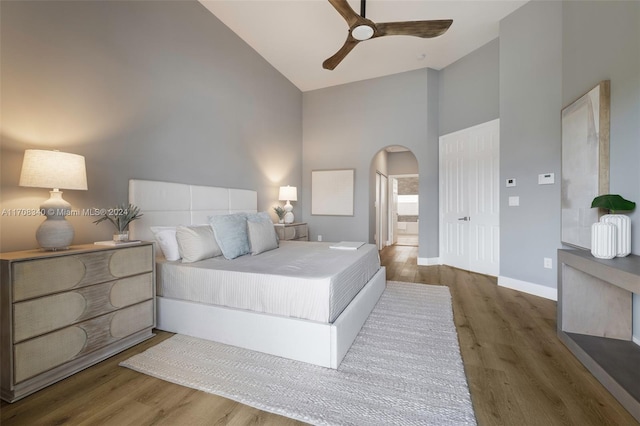 bedroom with ceiling fan, ensuite bathroom, high vaulted ceiling, and dark wood-type flooring