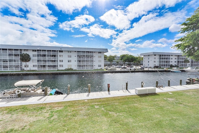 view of dock with a lawn and a water view