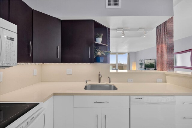 kitchen with white cabinetry, sink, white dishwasher, track lighting, and dark brown cabinets