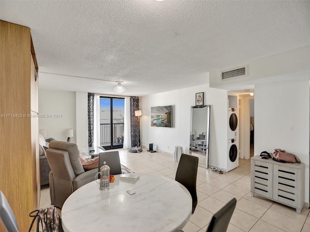 tiled dining space with a textured ceiling and stacked washer and dryer