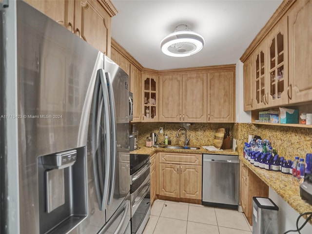 kitchen with light stone countertops, appliances with stainless steel finishes, backsplash, sink, and light tile patterned floors