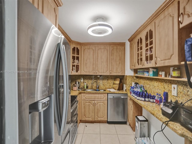 kitchen with sink, decorative backsplash, appliances with stainless steel finishes, light tile patterned flooring, and light stone counters