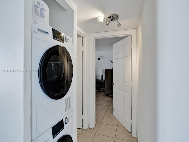 clothes washing area with light tile patterned flooring and stacked washer and dryer