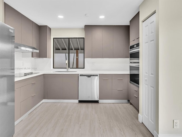 kitchen featuring ventilation hood, sink, gray cabinets, light wood-type flooring, and stainless steel appliances