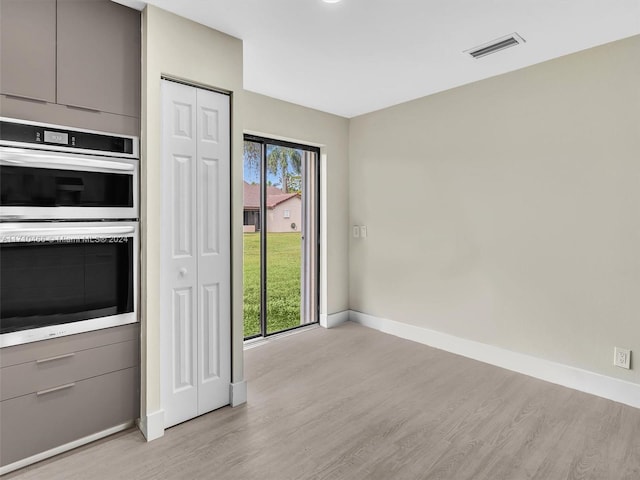 interior space with light hardwood / wood-style flooring, double oven, and gray cabinetry