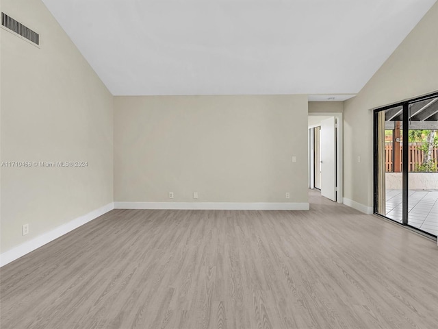 spare room with light wood-type flooring and lofted ceiling