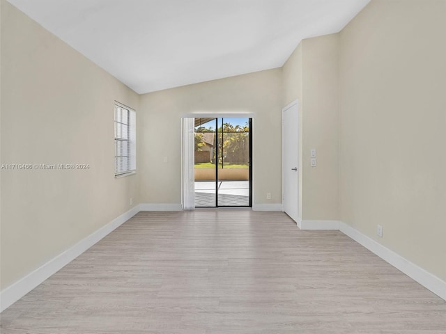 spare room with vaulted ceiling and light hardwood / wood-style flooring