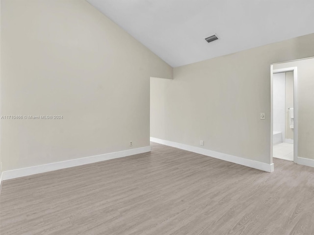 spare room with light hardwood / wood-style floors and vaulted ceiling