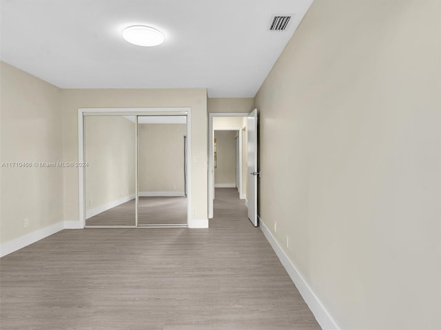 unfurnished bedroom featuring light hardwood / wood-style flooring and a closet