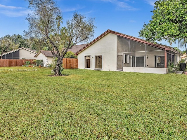 back of property with a lawn and a sunroom