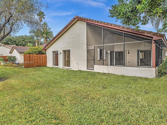 rear view of property with a yard and a sunroom