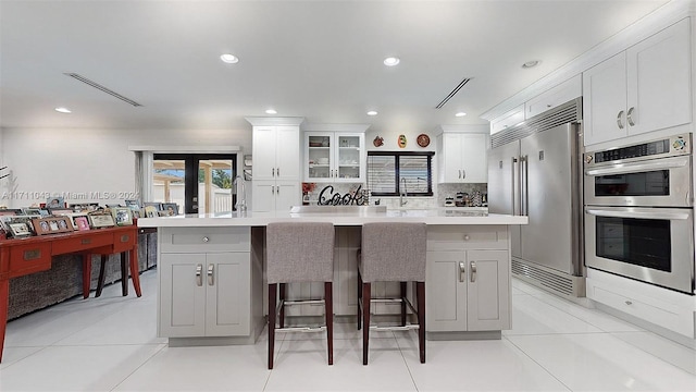 kitchen with white cabinets, a kitchen breakfast bar, a kitchen island, and appliances with stainless steel finishes