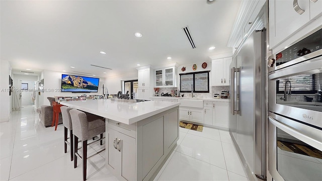 kitchen with stainless steel appliances, a kitchen island, tasteful backsplash, a breakfast bar, and white cabinets