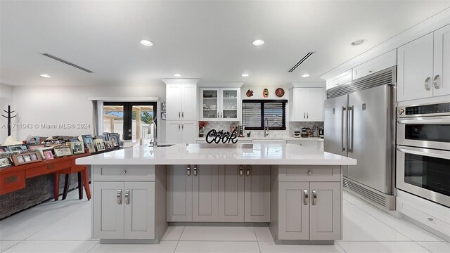 kitchen with appliances with stainless steel finishes, white cabinetry, french doors, and a large island