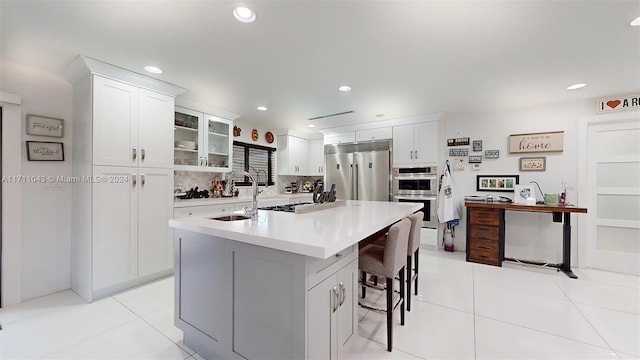 kitchen with a kitchen bar, white cabinetry, stainless steel appliances, and an island with sink