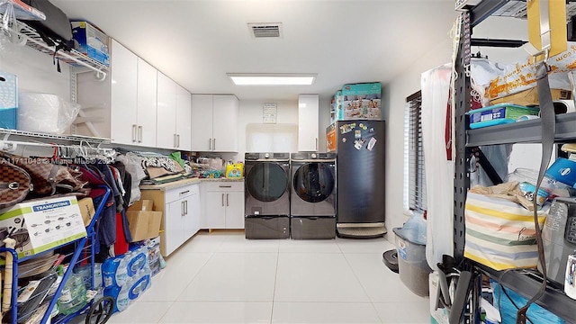 washroom featuring cabinets, independent washer and dryer, and light tile patterned floors