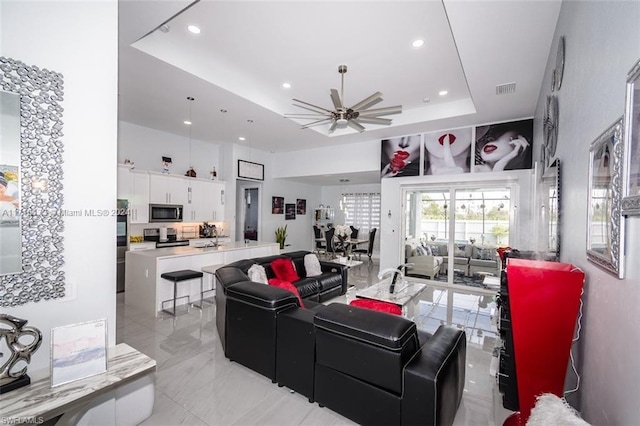 living room with a raised ceiling and ceiling fan