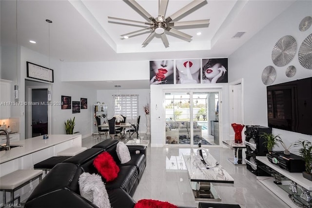 living room featuring ceiling fan and a raised ceiling