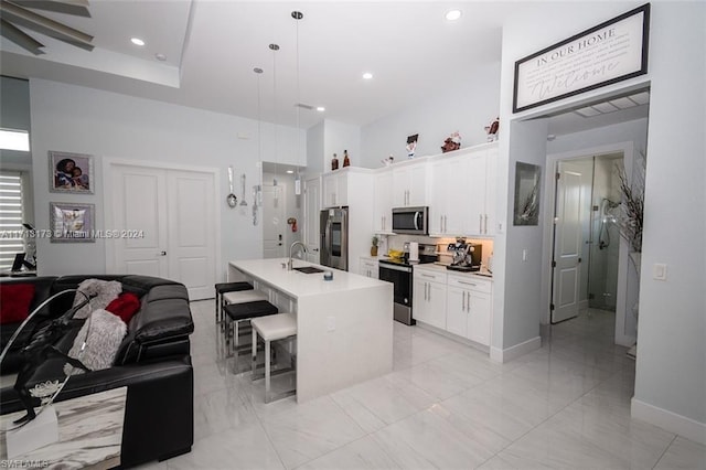 kitchen with a center island with sink, white cabinets, sink, decorative light fixtures, and stainless steel appliances