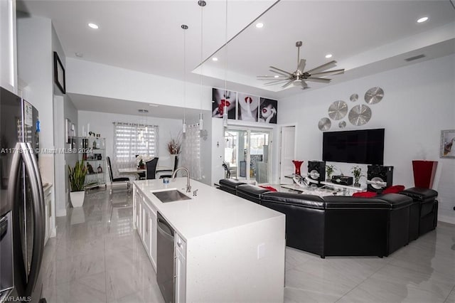 kitchen featuring appliances with stainless steel finishes, ceiling fan, sink, a center island with sink, and white cabinetry