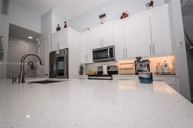 kitchen featuring white cabinets, appliances with stainless steel finishes, light stone counters, and sink