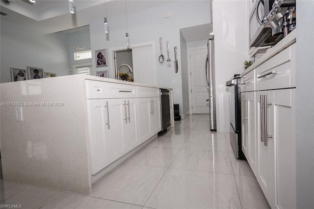 kitchen featuring white cabinets, pendant lighting, and stainless steel refrigerator