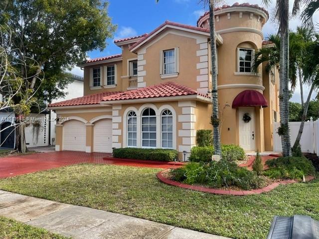 mediterranean / spanish home with a front lawn and a garage