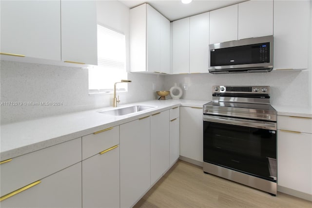 kitchen with decorative backsplash, white cabinetry, sink, and appliances with stainless steel finishes