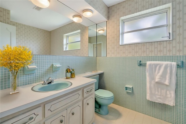 410 Miller Rd, Coral Gables, FL 33146 - bathroom with wallpapered walls, tile walls, vanity, toilet, and a wainscoted wall