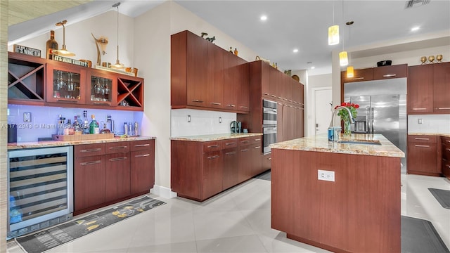 kitchen featuring pendant lighting, wine cooler, an island with sink, tasteful backsplash, and light tile patterned flooring