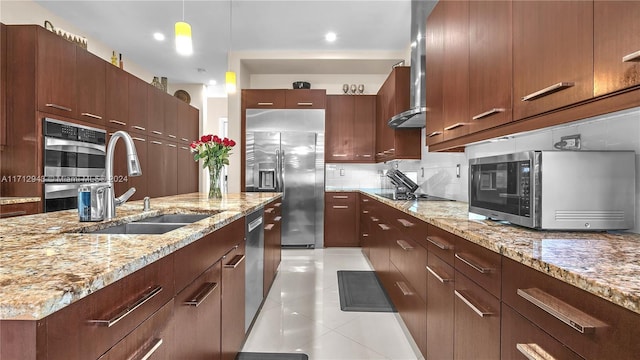 kitchen featuring appliances with stainless steel finishes, light stone counters, sink, light tile patterned floors, and hanging light fixtures