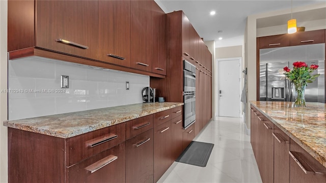 kitchen with stainless steel appliances, tasteful backsplash, light stone counters, decorative light fixtures, and light tile patterned flooring