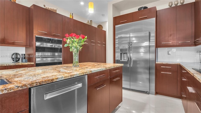 kitchen with tasteful backsplash, light stone countertops, light tile patterned flooring, and stainless steel appliances